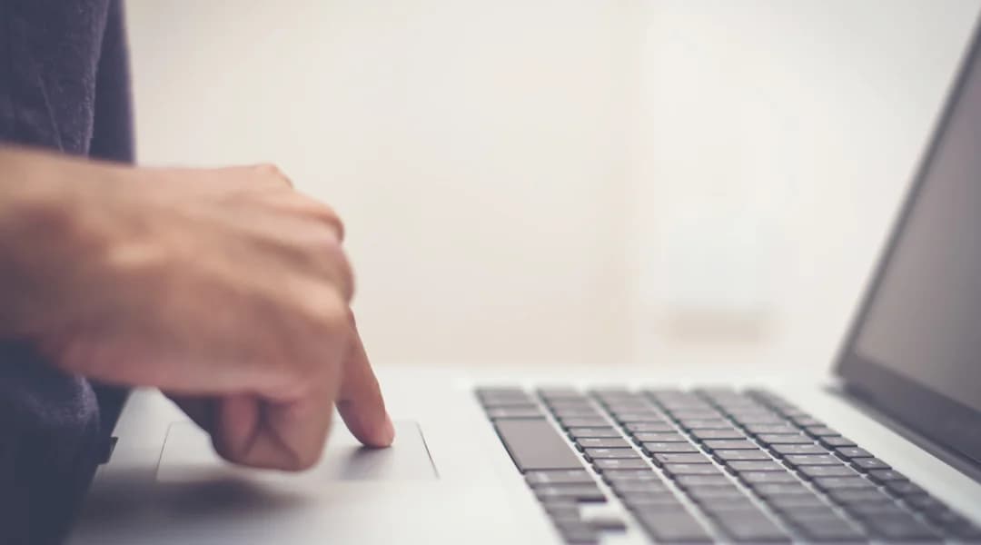 A person types on a laptop keyboard, engaged in an interac e-transfer transaction.