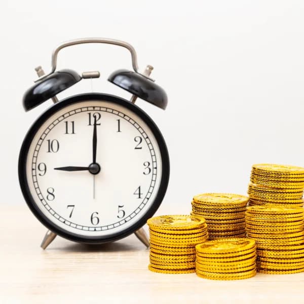 Une horloge et une pile de pièces d'or sur une table, symbolisant des emprunts instantanés et la gestion du temps.