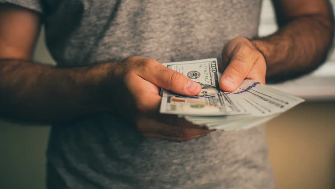 Un homme tenant une pile de billets de banque, symbolisant un remboursement de prêt.