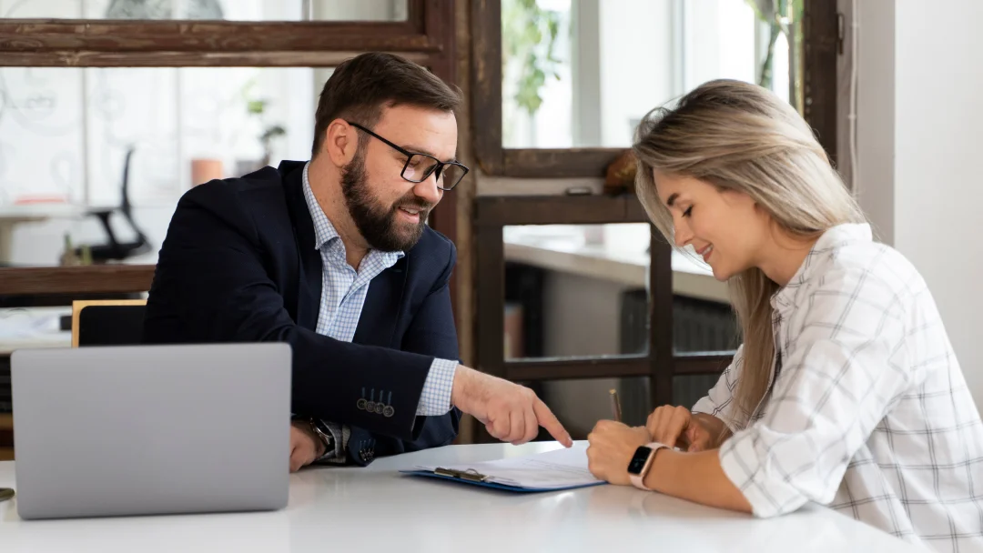 Un homme et une femme assis à une table, travaillant ensemble sur un ordinateur portable.