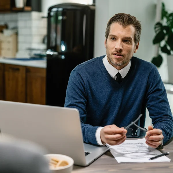 Un homme assis à une table avec des papiers et un ordinateur portable, travaillant en tant que prêteur indépendant.
